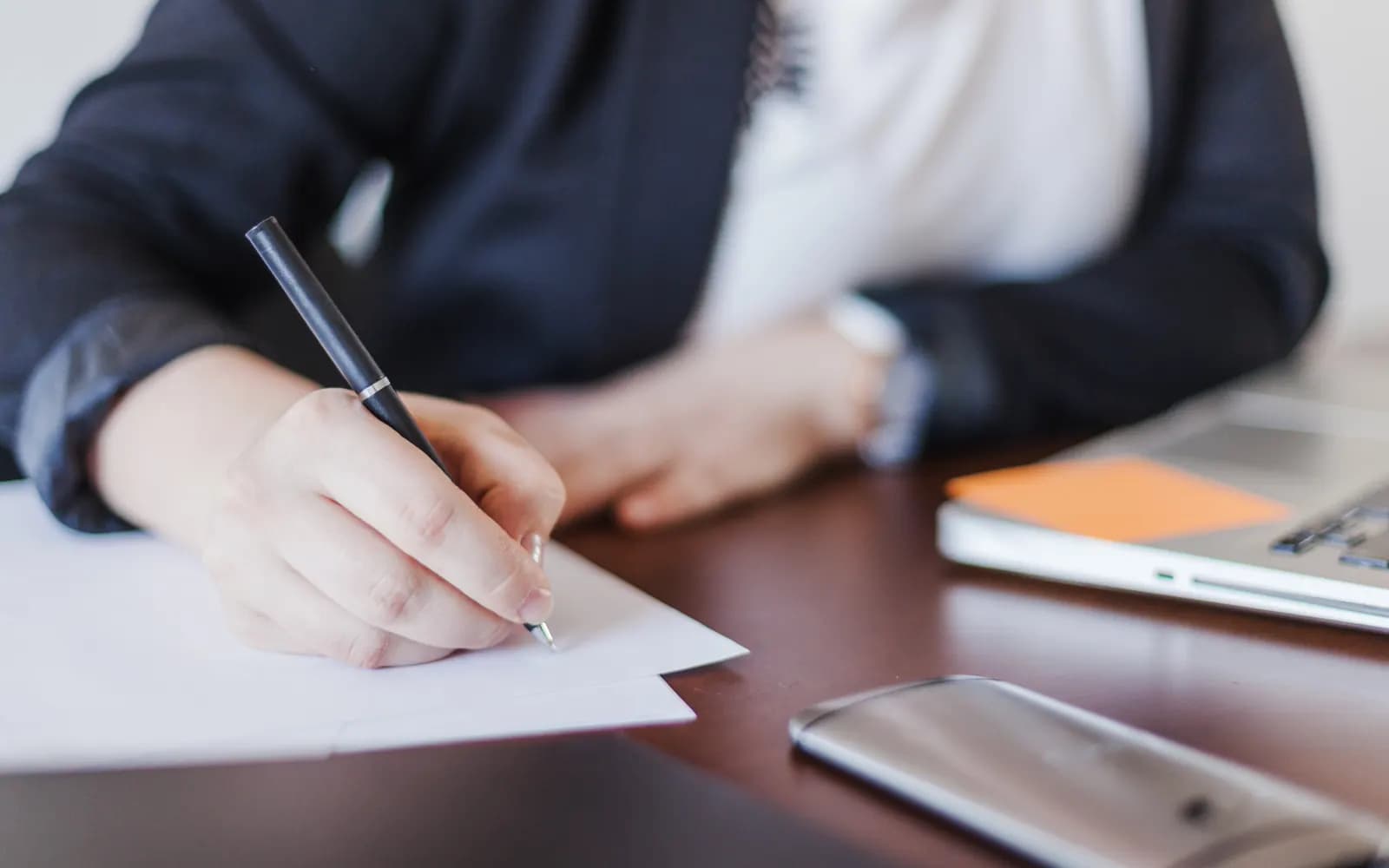 A person carefully writing a document at a desk